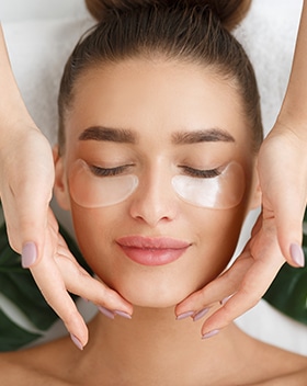 Woman with eye patches having face massage